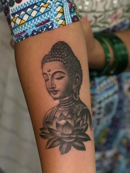 A full view of the finished Buddha and lotus forearm tattoo. The placement flows naturally with the arm's shape.