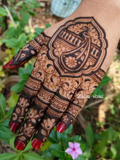 A close-up of the guest's mehndi, set against a natural green background.