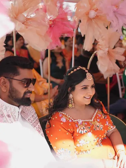 A lovely candid shot of the couple enjoying their Mehandi ceremony. The soft, oversized paper flowers in the background create a dreamy and artistic effect.