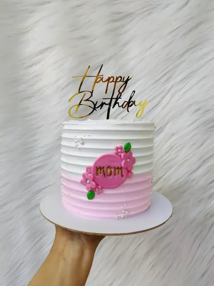A simple and elegant cake for mom. The pink ombre striped buttercream is decorated with a small floral plaque.