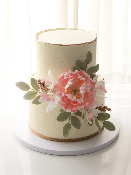 An elegant 50th birthday cake with a subtle stencil texture and a beautiful arrangement of handmade sugar flowers. This design is perfect for a sophisticated and understated celebration.