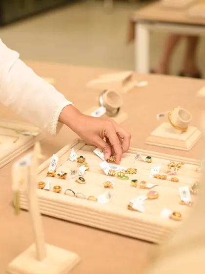 Exploring a tray of handcrafted rings and earrings. Our private viewings offer a tactile experience, allowing you and your friends to feel the quality of each consciously made jewel.