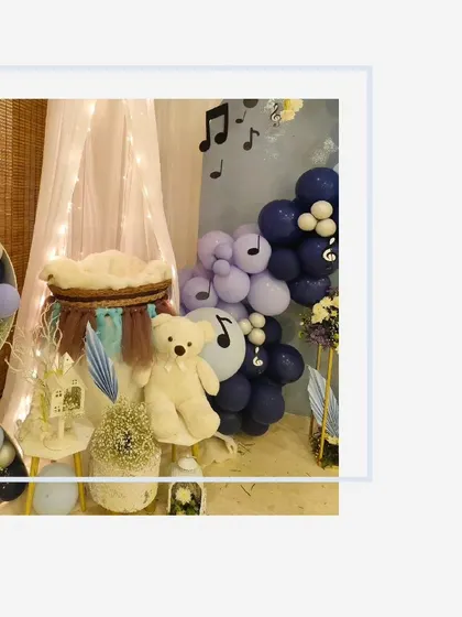 The cozy and cute cradle area, set up inside a teepee and decorated with balloons, a teddy bear, and musical notes.