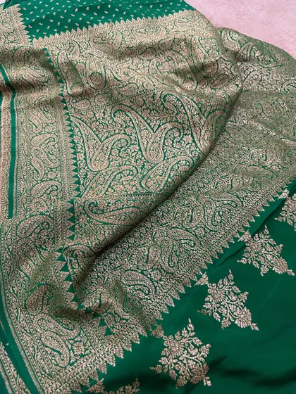 A close-up of the intricate paisley weaving on the pallu of the bottle green Banarasi silk saree.
