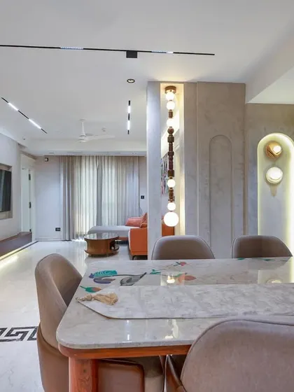 An open-plan living and dining area where custom furniture and lighting create distinct yet connected zones. The Greek key pattern on the floor adds a classic touch to the modern interior.