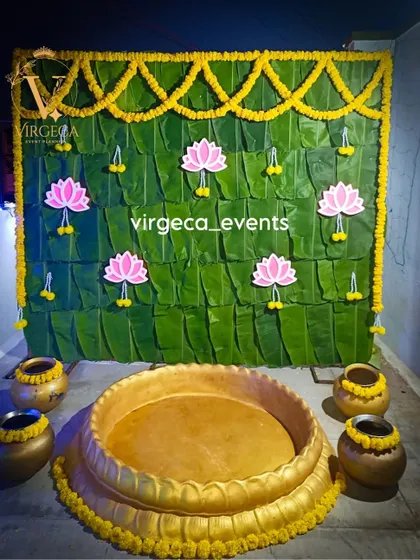 A simple and traditional Haldi decor with a backdrop of fresh banana leaves, marigold garlands, and lotus cutouts.