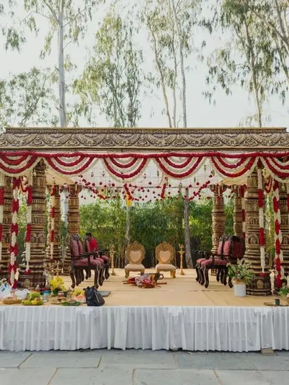 A full view of the traditional South Indian wedding mandap, showcasing its grand structure and intricate floral decorations set against a natural landscape.
