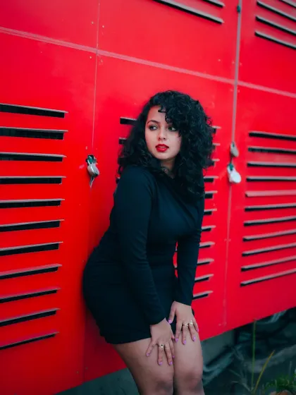 A duplicate of image 173, this portrait of a model in a black dress against a red wall is bold and confident.