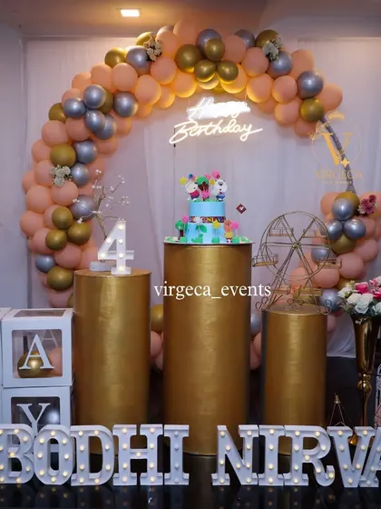 A stylish 4th birthday party with gold pedestals and a peach, silver, and gold balloon arch.