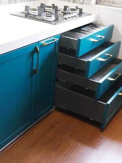 This kitchen, designed for a prominent social media influencer, showcases a classic shaker-style design with a rich teal PU finish. The image highlights the deep, organized drawers that are a hallmark of my commitment to functional storage.