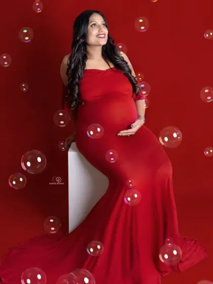 Having a little fun with bubbles! This playful shot in a classic red gown adds a touch of whimsy and joy to a studio maternity session.