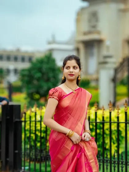A portrait of the bride in a beautiful red saree, with the groom in the background, set against the Vidhana Soudha. It tells a story of anticipation and love.