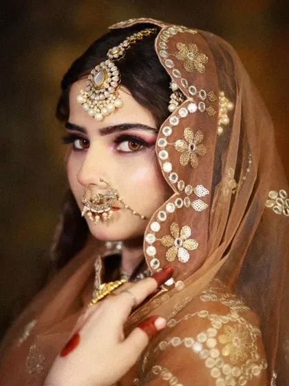 A close-up profile shot, focusing on the delicate features and the intricate details of the jewelry and dupatta.