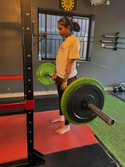 A female client performs a deadlift, demonstrating strength and proper form. We encourage and guide all our members to embrace heavy lifting.
