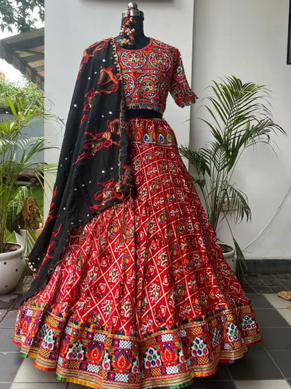 A beautiful red chaniya choli with intricate patola and embroidery work. The black dupatta with matching motifs provides a stunning contrast.