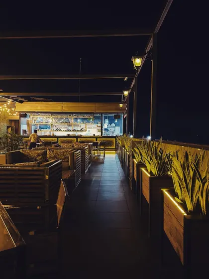 A long shot of the rooftop cafe's seating arrangement, showing how planters are used to line the edge and create a sense of enclosure and privacy.
