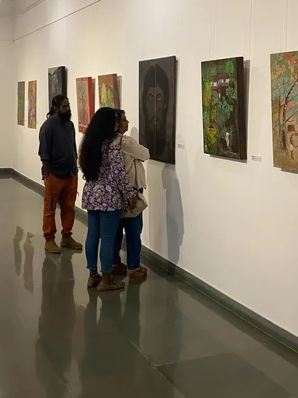Artist Unnikrishnan C (in orange pants) talking to visitors about his and his mother's work.