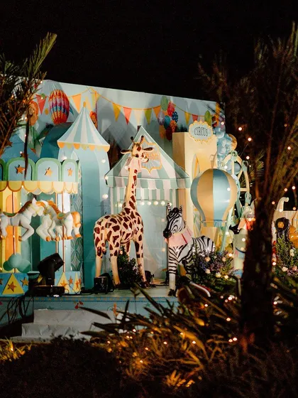 The carnival looks just as magical at night! With twinkling lights illuminating the palm trees and the grand stage, the party transforms into an enchanted evening spectacle.