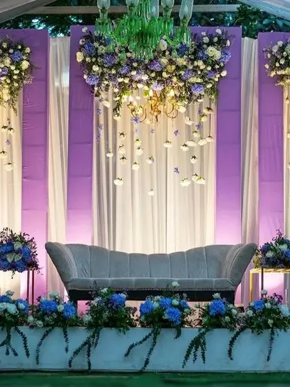 We created this dreamy reception stage with hanging floral chandeliers and soft purple and blue lighting. The cascading flowers and elegant seating make it a truly magical setting for an evening event.