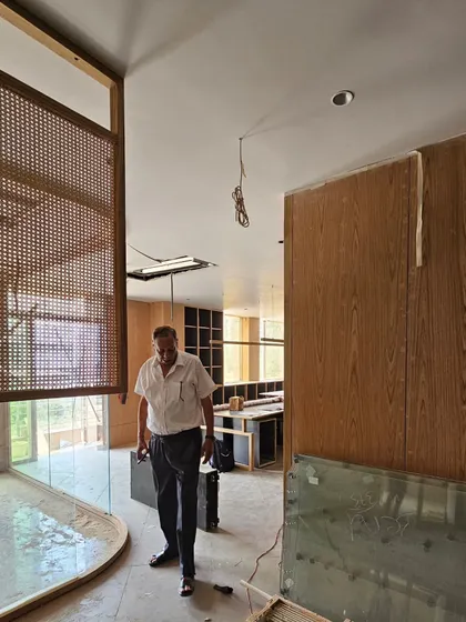 An artisan at work on a project site featuring wood and rattan panels. We collaborate closely with skilled craftspeople to ensure our designs are executed with precision and care.