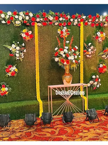A beautiful photo wall with a green turf background and artistic floral arrangements. This setup adds a touch of nature and elegance to any outdoor event.