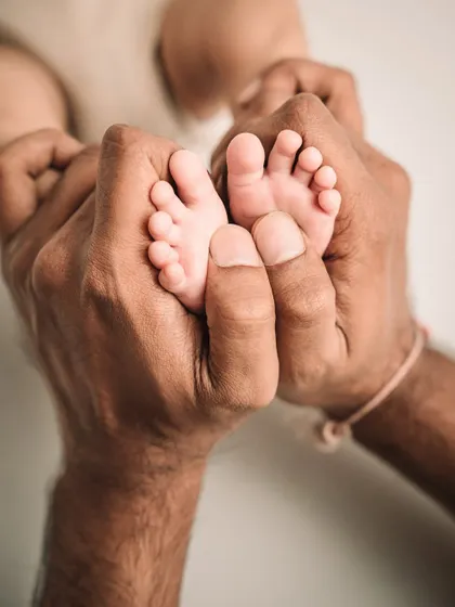 A father's hands gently holding his baby's feet. A simple, powerful image of paternal love.