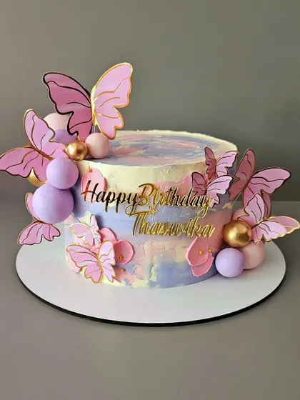 A beautiful butterfly-themed cake for Thanushka's birthday. This butterscotch cake features a pastel watercolor effect and is adorned with delicate pink and purple butterflies.