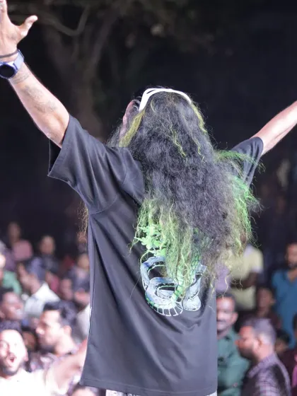 A view from behind, showing me with my arms raised to the crowd, my long hair a prominent part of my stage presence.