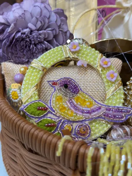 This close-up shows a beautiful hand-embroidered bird brooch, another example of the unique, artisanal items I source for my hampers.