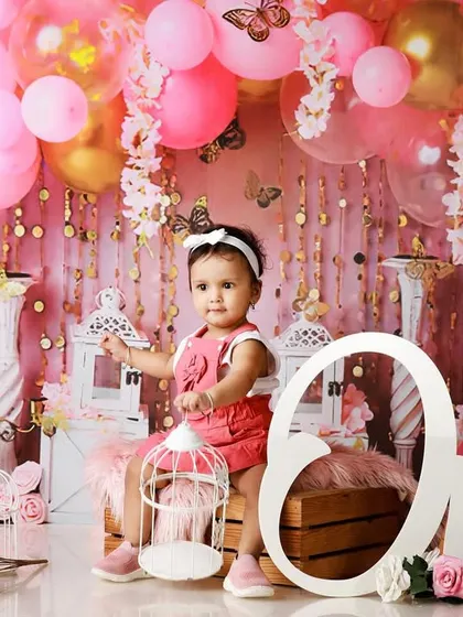 A glamorous first birthday celebration with a pink and gold butterfly theme. The balloon arch and elegant props create a stunning backdrop for the birthday girl.