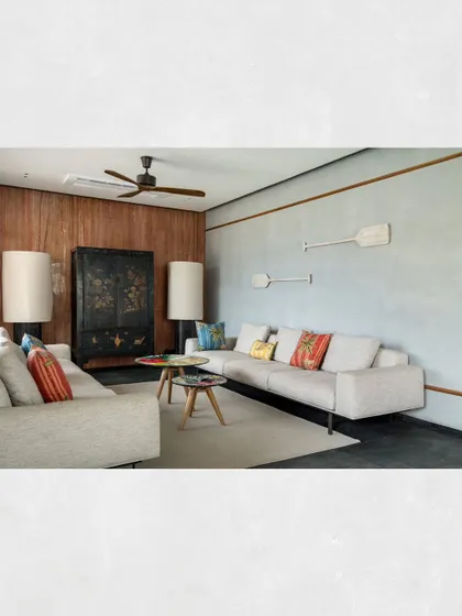 A view of the private lounge in Kamala Residence, highlighting the contrast between the dark wood-paneled wall and the light, cement-finished wall.