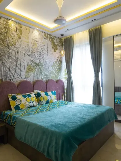 This bedroom makes a bold statement with a vibrant tropical leaf wallpaper behind a scalloped purple headboard. The mirrored wardrobe doors add a touch of glamour and make the room feel more spacious.