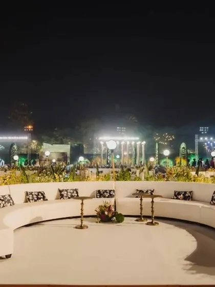 The clean, white curved sofas create a striking contrast against the dark night, providing a chic and inviting seating area for guests at the reception entrance.