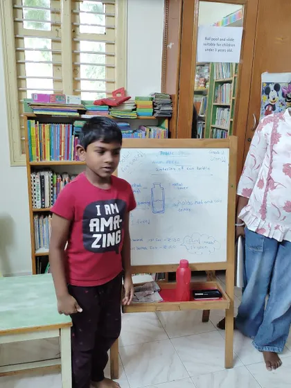 A young speaker confidently stands by the whiteboard to present his topic. His t-shirt says it all: "I AM AMAZING."