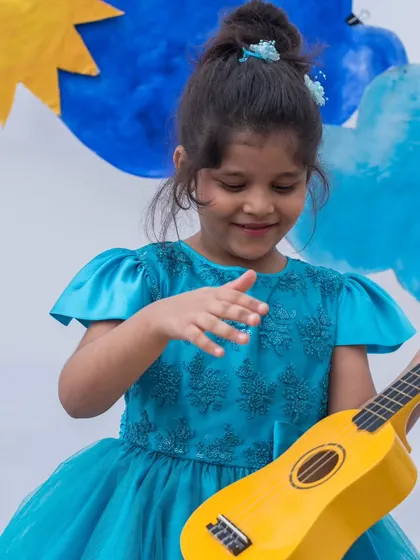 Strumming a tune in style. This image captures the playful side of this elegant turquoise dress, showing that beauty and comfort can go hand in hand.