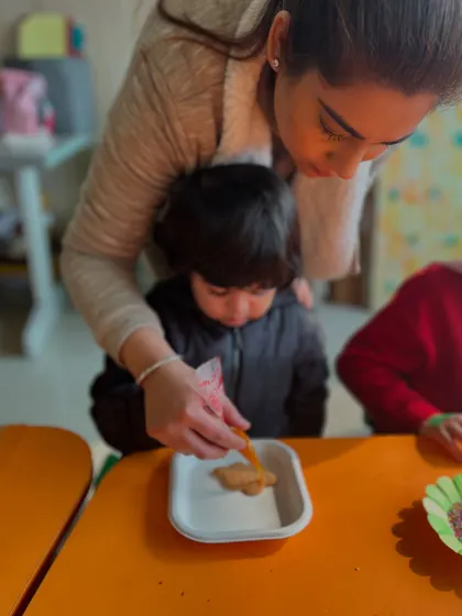 A mother helps her child with cookie decorating, a perfect example of the parent-child bonding we encourage.