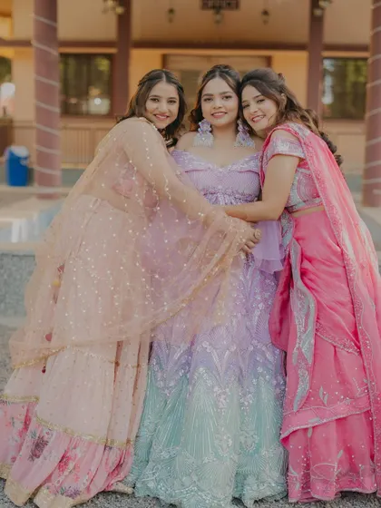 A beautiful moment of friendship and love as the bride is embraced by her bridesmaids. Their coordinated pastel outfits add to the visual harmony of this happy shot.