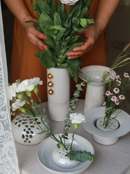 An assortment of white porcelain vases from the 'Celebrations' collection, some with gold accents and others with playful polka dots, perfect for floral arrangements.