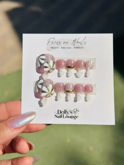 A lovely floral press-on pedicure set. This design has a shimmery pink base with delicate, hand-painted white and gold flowers on the big toe.