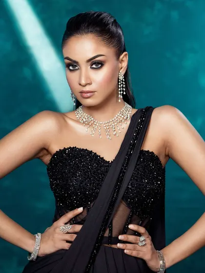 A confident and strong portrait focusing on the sequined bustier and diamond jewelry, set against a cool teal background.