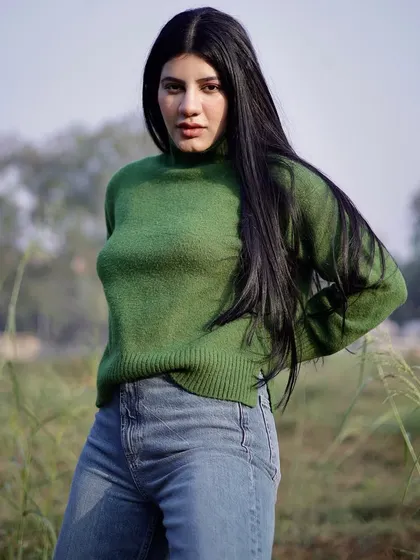 An outdoor fashion shoot in a natural setting. The contrast between the green field and the model's sweater creates a vibrant, eye-catching portrait.