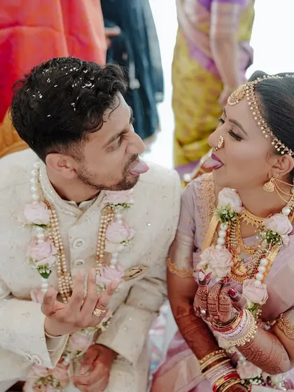 A high-quality candid shot of a couple's playful interaction during their wedding ceremony.