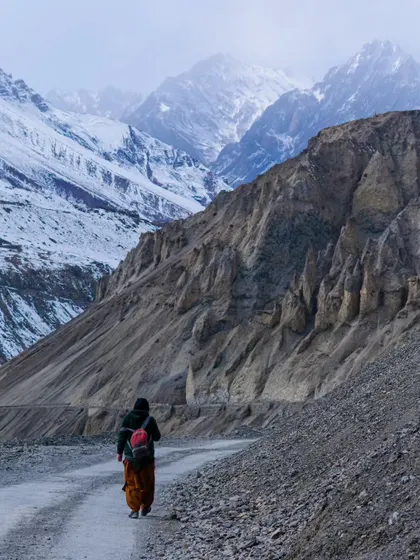 A lone traveler walking along a desolate road in Spiti, dwarfed by the immense landscape. This image evokes a sense of solitude and personal journey amidst the grandeur of the Himalayas.