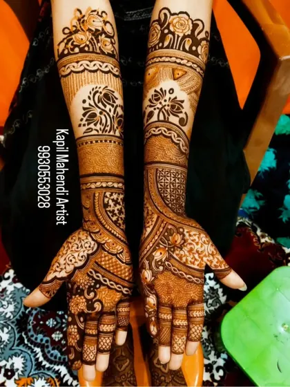This is a classic full-arm mehendi style with matching symmetrical patterns on both hands. The design features floral bands and detailed work on the fingers for a complete look.