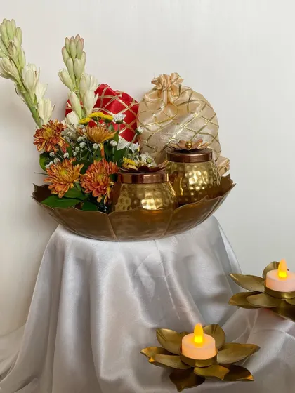A different perspective of the traditional urli hamper. The arrangement is perfect as a centerpiece, combining the fragrance of fresh flowers with the promise of delicious treats inside.