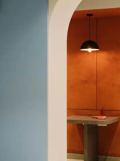 A view through an archway reveals the contrast between the cool blue of the pantry area and the warm red of a breakout nook, showcasing our use of color blocking to define space.