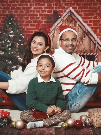 A classic family Christmas card photo. Sitting back-to-back against a festive brick wall backdrop, this family looks picture perfect.