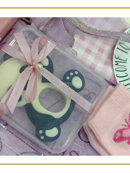 A close-up of a baby girl gift set, showing a cute panda-themed teether wrapped with a pink ribbon.