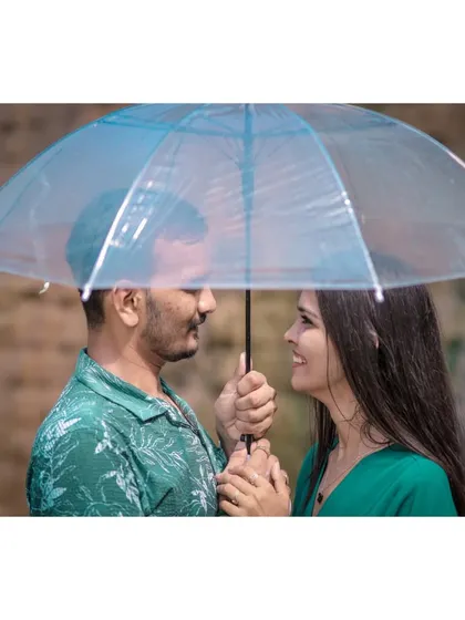 A close-up, intimate shot of a couple sharing a smile under a single umbrella, capturing a sweet and romantic moment.