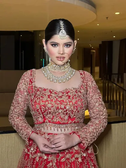 A front-facing portrait of the bride, showcasing her diamond choker and maang tikka.